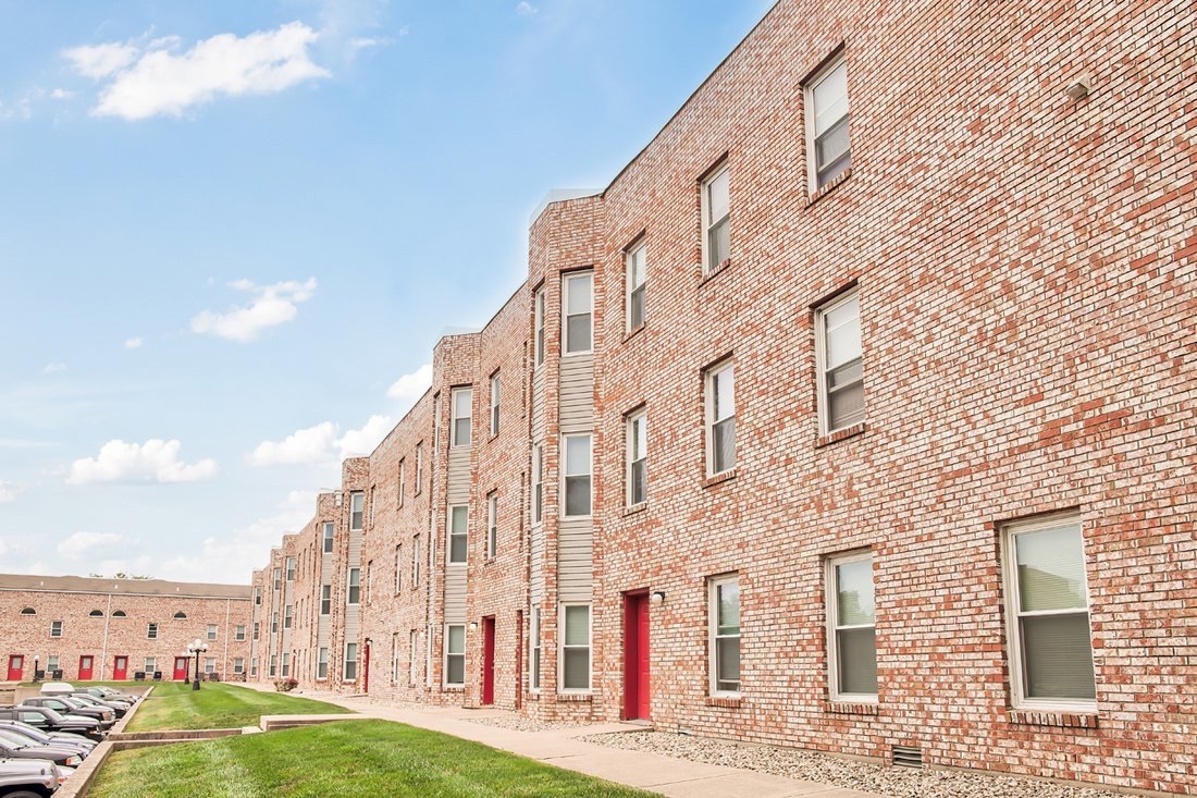 a brick apartment building with cars parked in front at The Beacon Hill Apartments