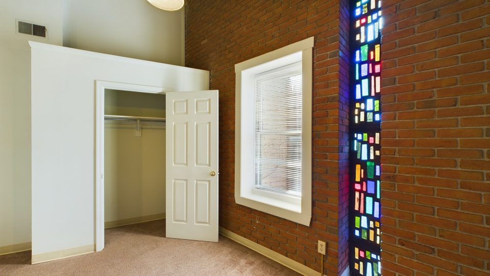 a room with a stained glass window and a closet at The Beacon Hill Apartments
