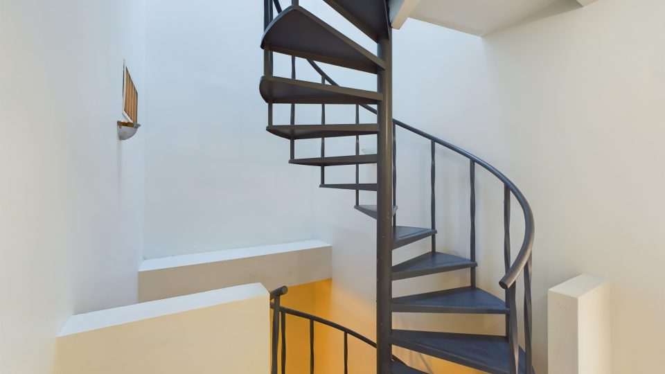 a spiral staircase in a white room with a metal railing at The Beacon Hill Apartments