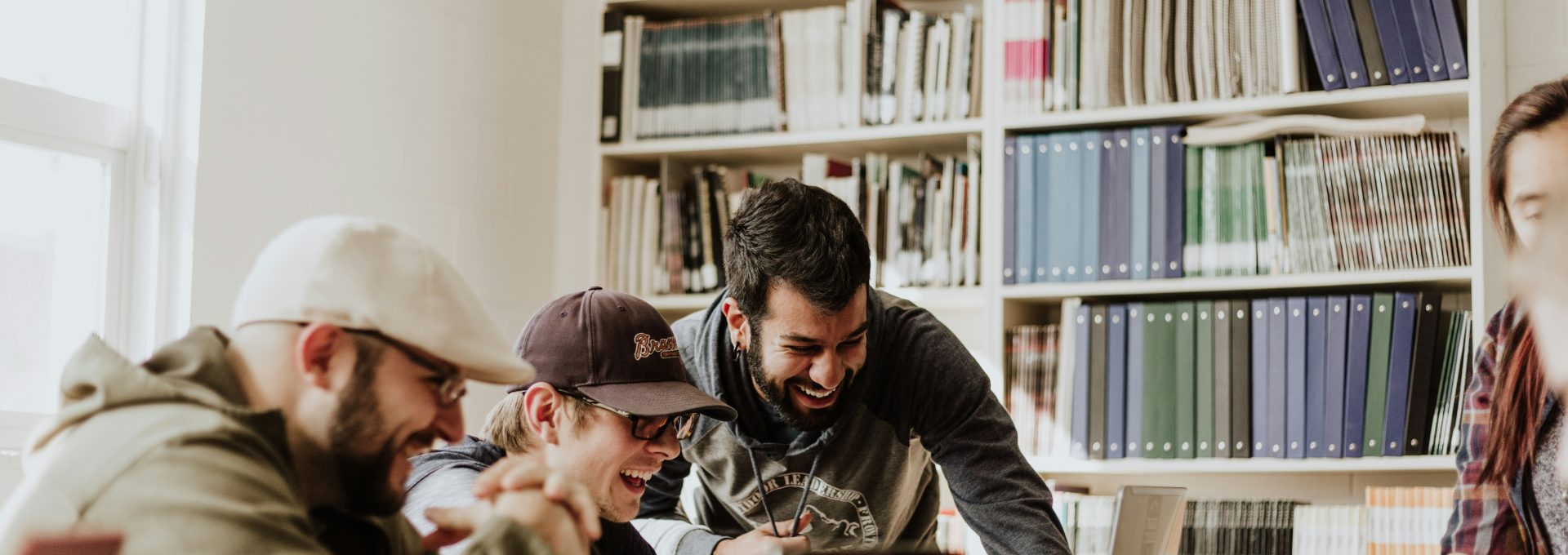 three men laughing while looking in the laptop inside room